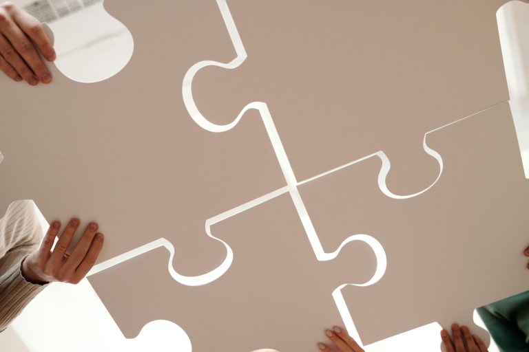Small group of people building a large beige puzzle together